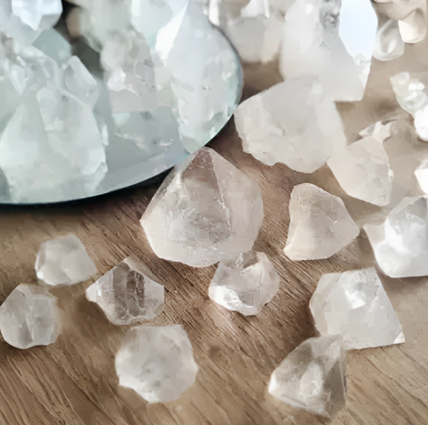 A collection of clear apophyllite crystal points on a wooden surface, with a blurred background.