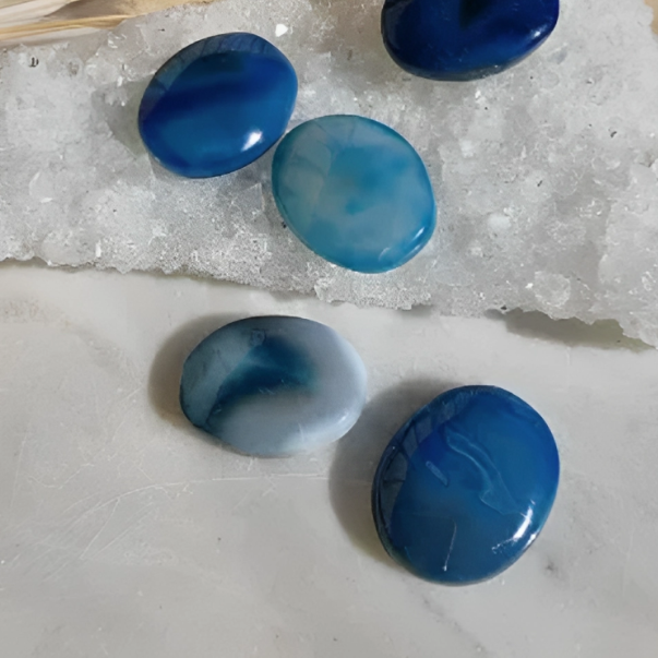 A collection of blue agate palm stones placed on a white surface.